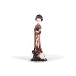 A Chinese ivory carving of a lady, 19th Century, standing beside a garden rock, one hand holding a