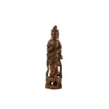 A Chinese carved wooden figure of Guanyin, 20th Century, standing on a rocky base, wearing long