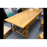 A contemporary rectangular elm refectory dining table, on turned legs with twin uniting stretcher,