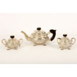 An Indian embossed white metal three-piece tea set, with ebonised mounts (3)