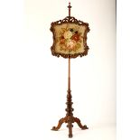 A mahogany pole screen, 19th Century, with a carved and parcel gilded pierced cartouche form