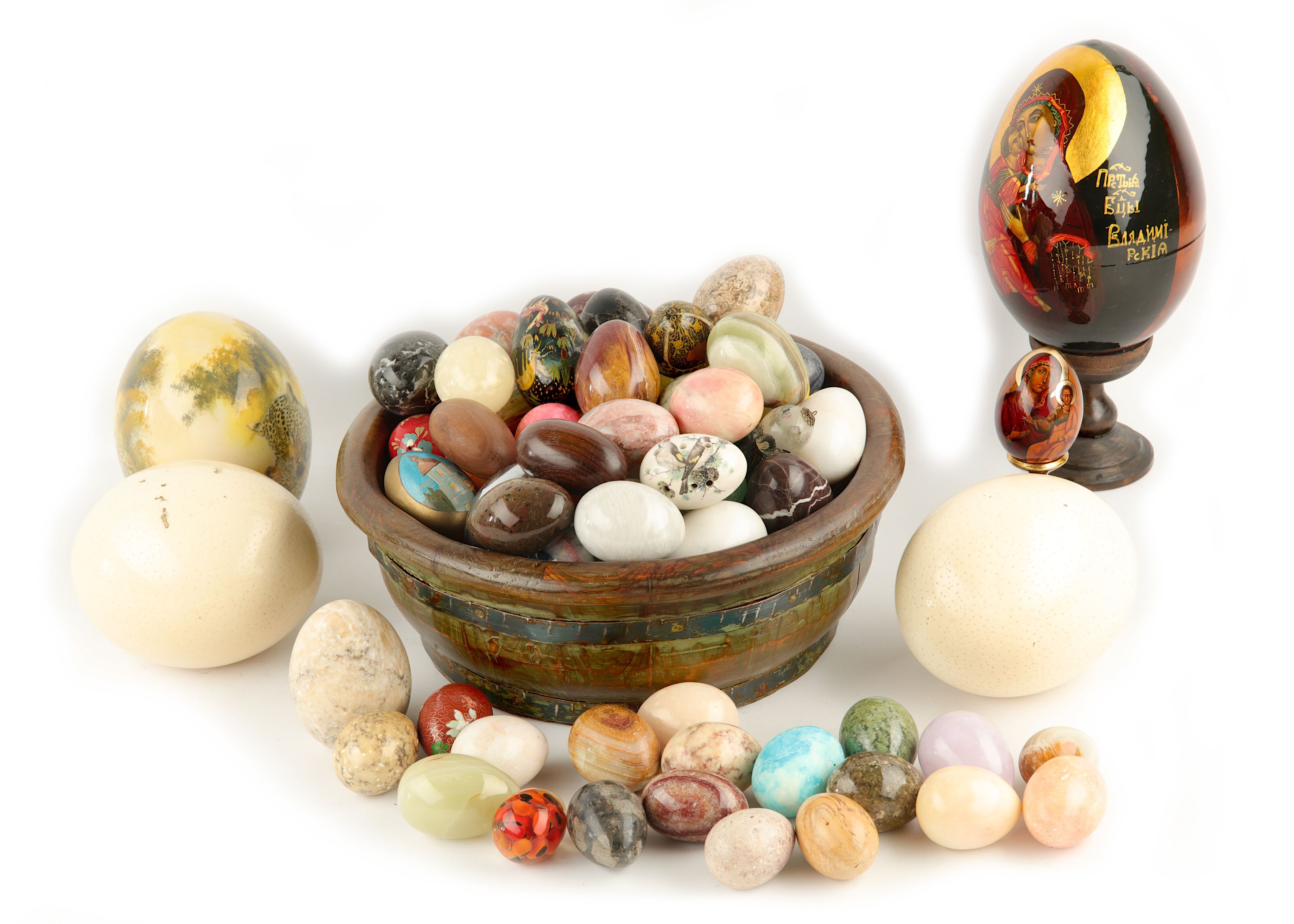 A large collection of glass and hardstone eggs, together with three ostrich eggs, one painted with