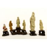 A collection of Chinese soapstone carvings, including a Guanyin holding a vase, a standing Buddha in