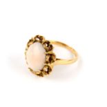 A coral ring, the oval cabochon coral Corallium rubrum, within a scrolling gallery, stamped 750,