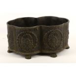 A black metal painted metal planter trough, cartouche shape cast with floral panels, supported on