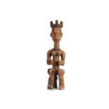 AN IGBO IKENGA SHRINE FIGURE, NIGERIA Circa 1940s The stylised wood figure sits on an integral stool