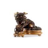 A Japanese bronze model of a lion dog and a ball, 19th Century, a shishi dog seated with his front