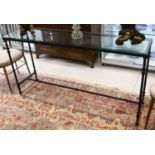 A modern design cast-iron console table, with a heavy cut glass top, raised on slim tapering legs,