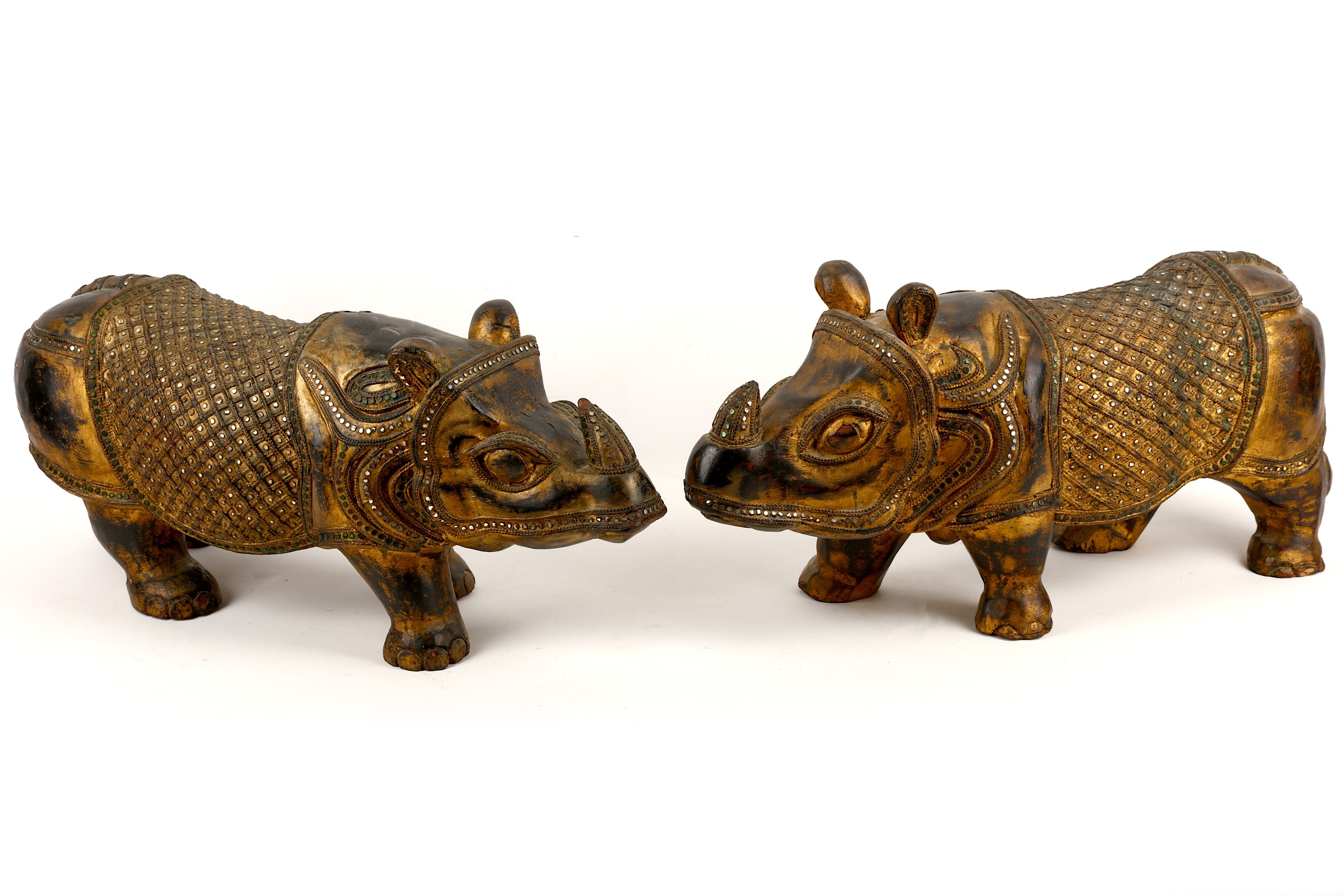 A pair of Indian carved wood parcel gilt models of standing Rhinoceros, 56cm long (2)