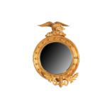 A Regency giltwood convex wall mirror, with moulded cavetto frame inset with balls, and an eagle