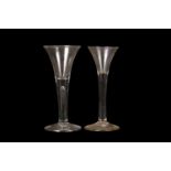 A pair of 18th Century wine glasses, each with drawn trumpet bowls over plain stems and conical