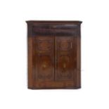 A George IV oak and mahogany hanging corner cabinet, the dentil pediment over a pair of panelled