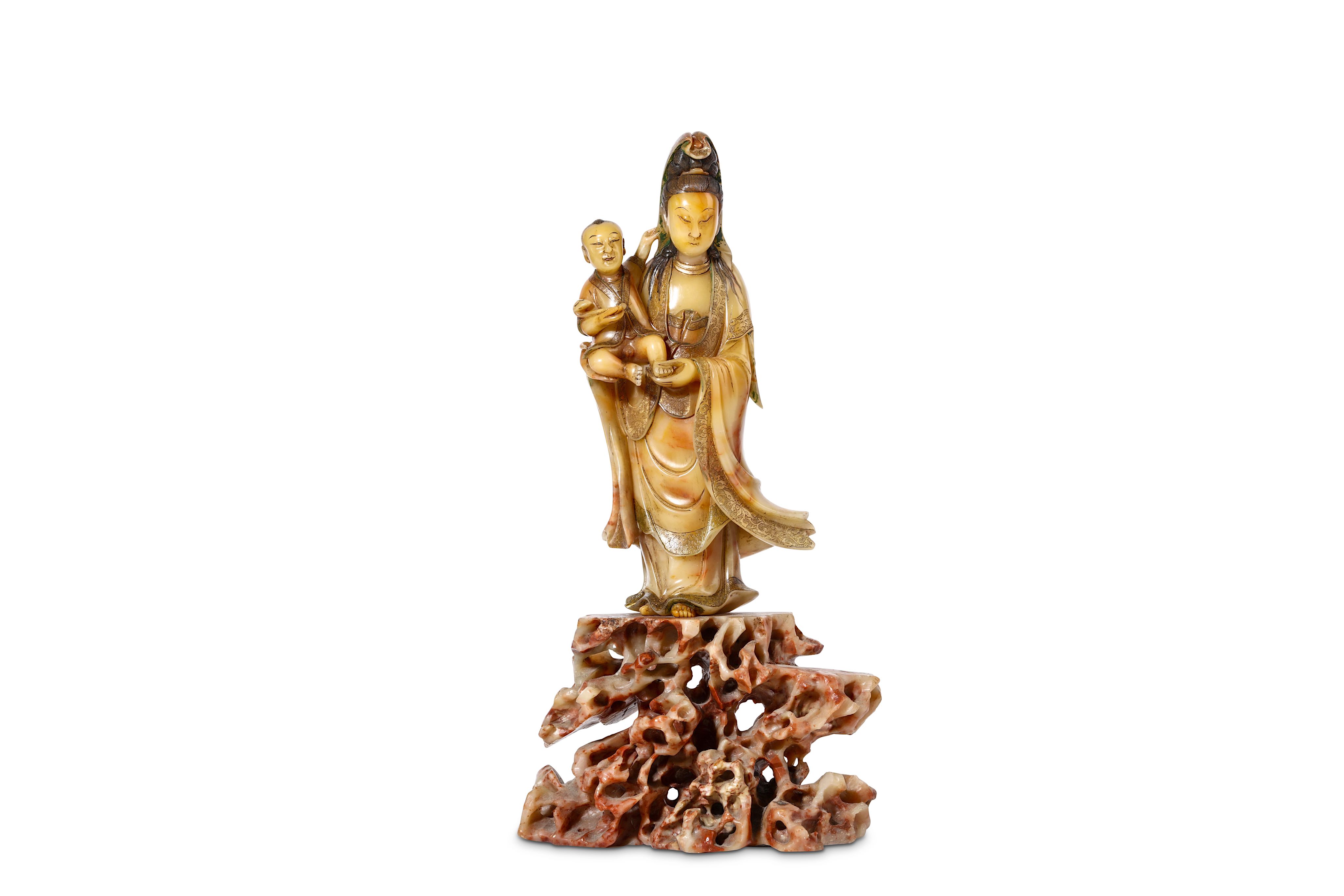 A CHINESE SOAPSTONE FIGURE OF A GUANYIN AND CHILD. Early Qing. Standing holding an infant in her