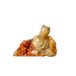 A CHINESE SOAPSTONE FIGURE OF A RECLINING IMMORTAL. Kangxi. The bearded figure seated against a