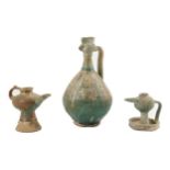 AN IRANIAN COCKEREL-SHAPED POTTERY EWER AND TWO POTTERY OIL LAMPS