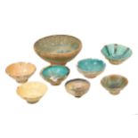 SEVEN IRANIAN SMALL POTTERY BOWLS AND ONE LARGE TURQUOISE AND BLACK-PAINTED POTTERY BOWL