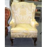 A mahogany framed wing armchair with cream damask upholstery,