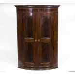 A mahogany and inlaid bowfront corner cabinet with box strung panelled doors and Grecian key dentil