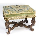 A 19th Century carved framed stool, the needlework upholstered seat on scrolling leaf carved legs,