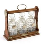 An oak cased tantalus fitted three cut glass decanters with silver labels