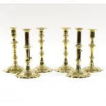 Two pairs of petal based brass candlesticks and two similar candlesticks,