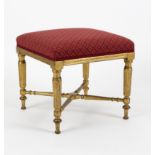 An Louis XVI style upholstered stool, on gilded fluted legs united by an X-shaped stretcher,