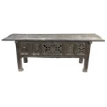 A Tudor style oak counter or hutch table, the hinged planked top above a carved panelled front,