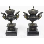 A pair of bronze urns with pine cone finials and seated leopard handles on slate plinths,
