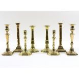 A pair of George III brass candlesticks with beaded square bases and three further pairs of brass