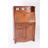 An Art Nouveau oak bureau, the galleried top with pierced decoration above a fall with strap hinges,