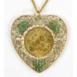 A 1910 gold sovereign pendant mounted within an openwork gold heart shaped mount set emeralds to a