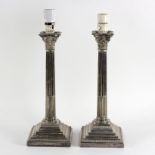 A pair of silver plated Corinthian column candlesticks with stepped square bases,