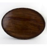 A 19th Century mahogany oval tray with wavy gallery, reinforced brass banding to one side,