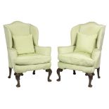 A pair of 18th Century style wing back armchairs on carved cabriole legs,