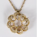 A diamond pendant/brooch of circular pierced form set round brilliant cut diamonds to a 9ct gold