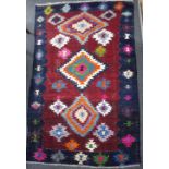 A Navajo style rug, worked with geometric patterns to a red ground within a blue border,