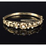 A 9ct gold bangle with pierced foliate detailing set with cultured pearls,