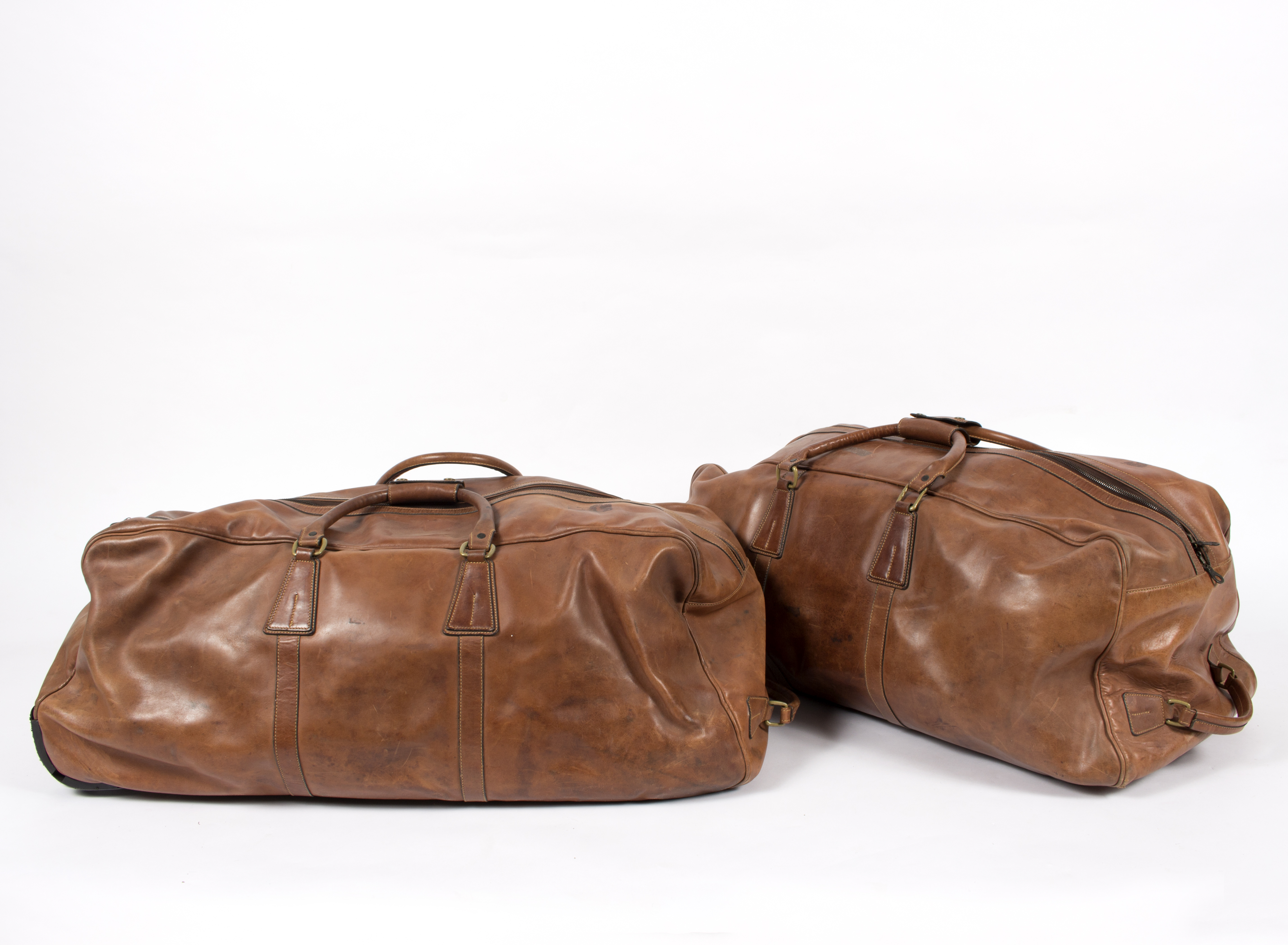Two brown leather travel bags, by Pickett, London, both with wheels,