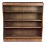 An oak bookcase with fluted frieze and base, fitted adjustable shelves enclosed by glazed doors,