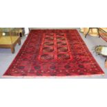 An Afghan red ground carpet, the central field of ten elephant foot medallions,