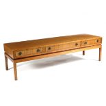 A low teak coffee table, fitted three double sided drawers on square legs,