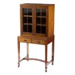 A Cotswold School walnut cabinet enclosed by a pair of doors with fine cross shaped bars,