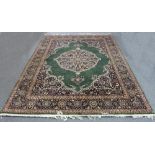 An Eastern style carpet with central medallion on a green ground within a figured floral border,