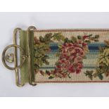 A late Regency needlework bell pull with brass mounts,