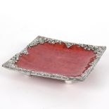 A square dish with Eastern white metal border and ball feet,