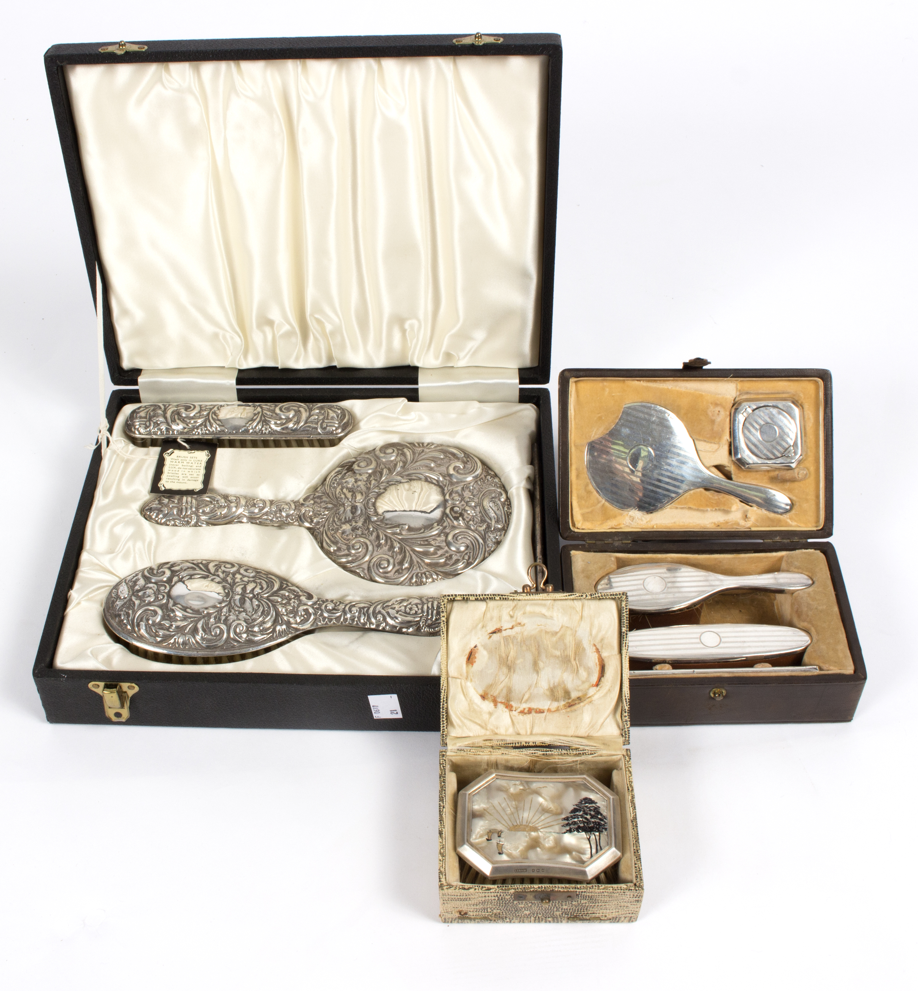 A silver three-piece dressing set with repoussé decoration, in fitted case,