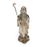 A silver coloured metal figure of a bearded immortal wearing a Mandarin coat and holding a staff,