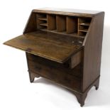 An oak bureau fitted pigeonholes beneath the fall flap with three long drawers under,