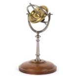 A steel and brass gyroscope, on circular wooden base,