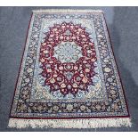 A Qum rug with crimson ground geometric field within a floral border,